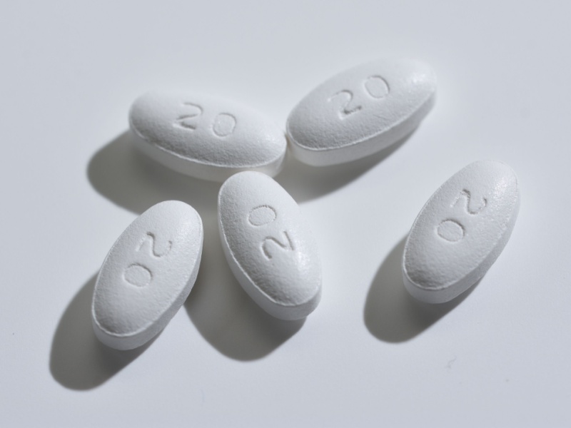 A close up of white statin pills on a table.