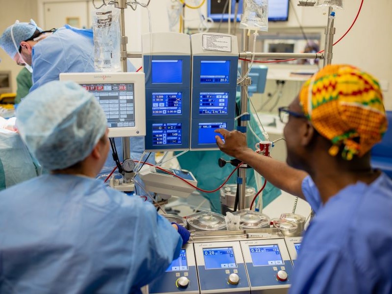 Professor Akowuah and other clinical staff in blue scrubs monitoring a heart lung machine during a heart bypass surgery at The James Cook University Hospital, Middlesbrough.