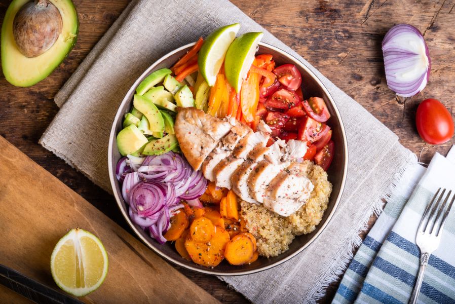 Baked chicken breast with quinoa salad, avocado and vegetables.