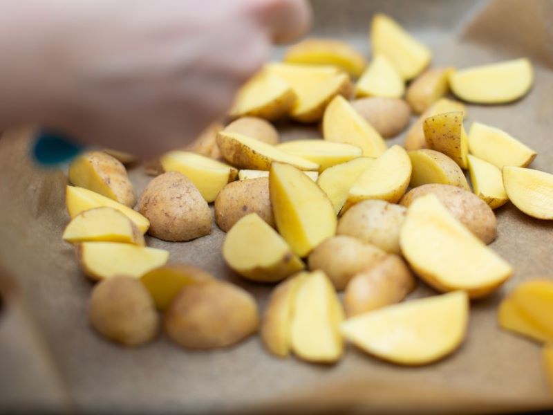 A person preparing unpeeled potatoes.