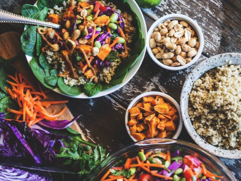 High fibre foods on a table, including salad, nuts and quinoa.