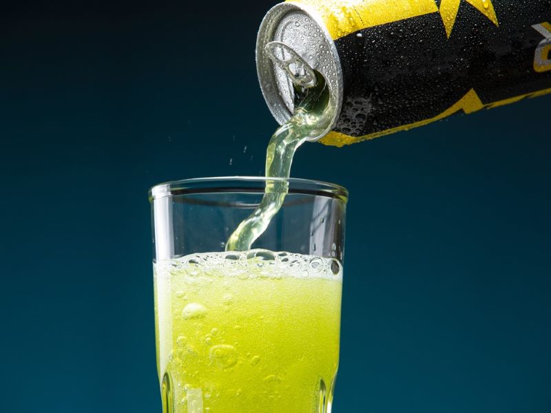 A can of energy drink being poured into a glass.