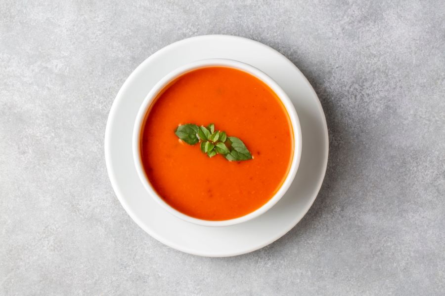 Bowl of tomato soup with fresh basil garnish.