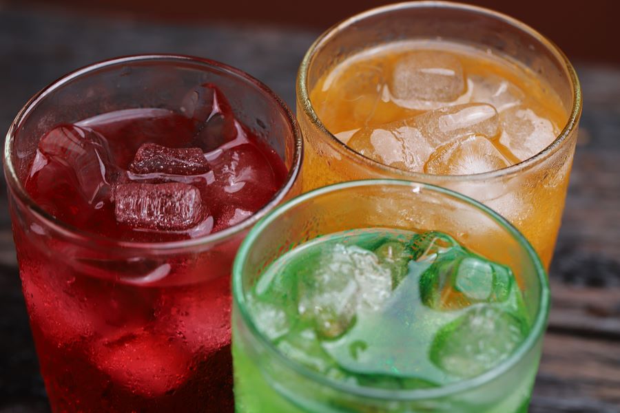 Three glasses of colourful sugary drinks.