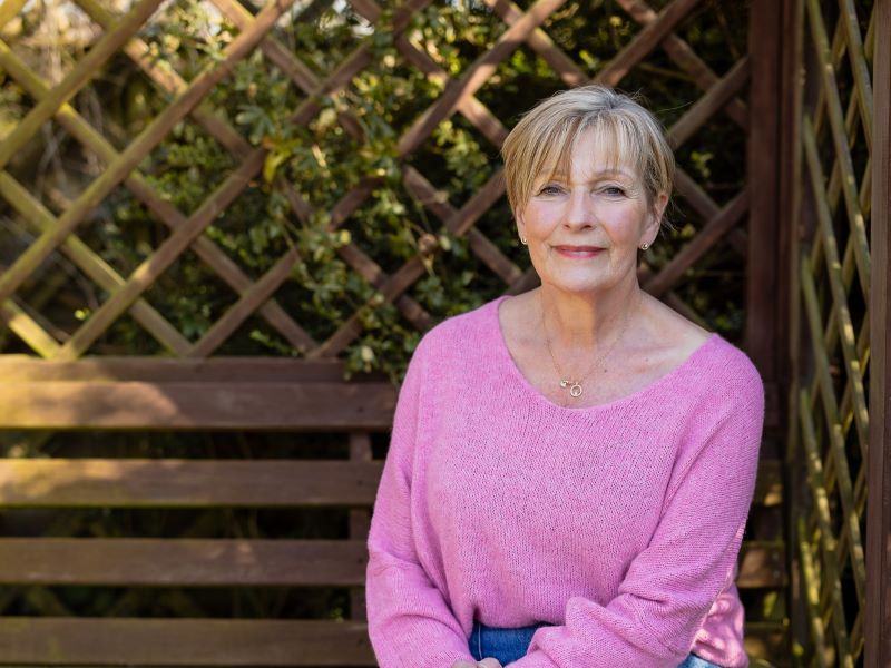 Linda sitting on a bench in her garden.