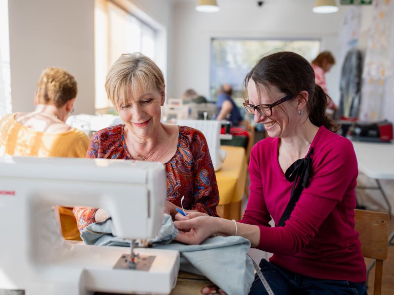Linda and Pauline sitting by a sewing machine.