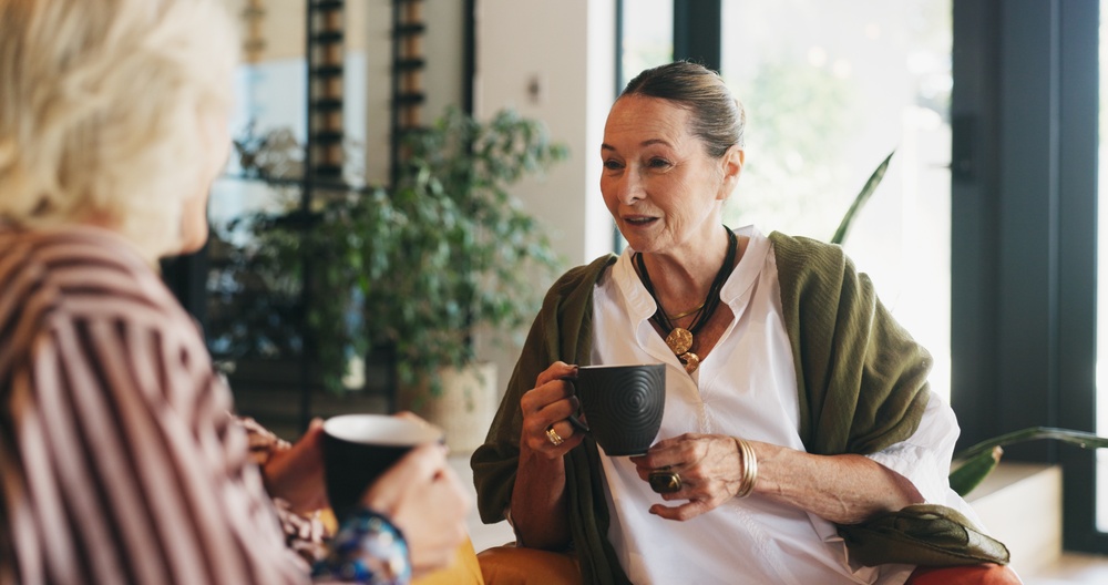 Two female friends talking while drinking a cup of tea