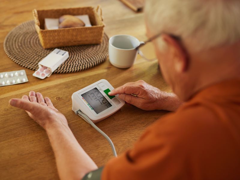 A man checking his blood pressure at home with a blood pressure monitor.