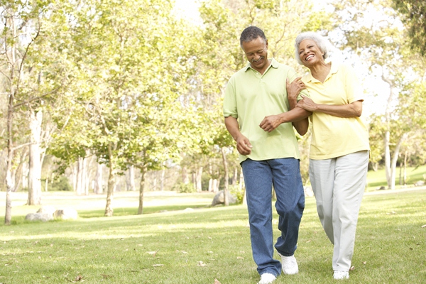 Older couple take a walk outdoors on a sunny day