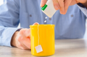 Putting artificial sweetener into a cup of tea