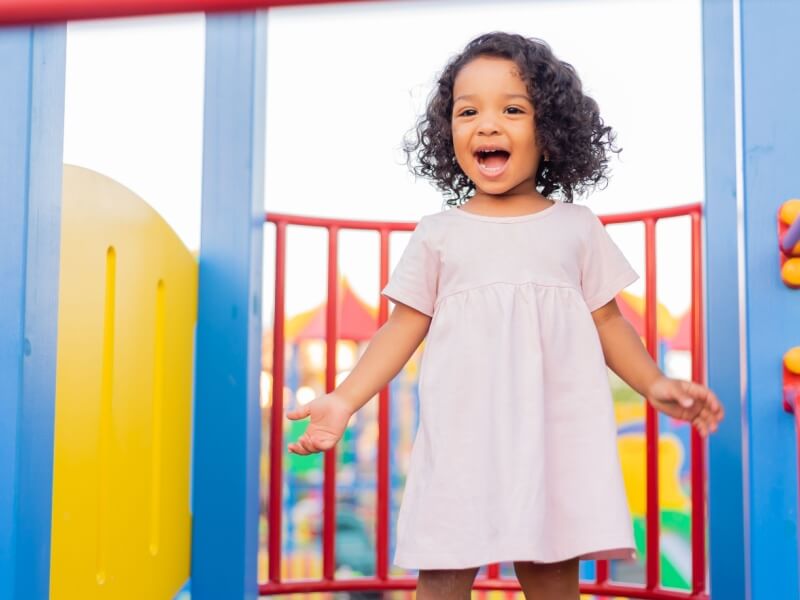 A child smiling as she plays in the playground