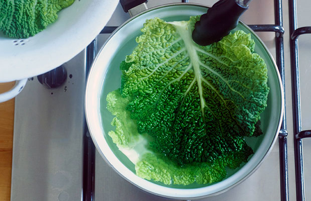 Blanching whole cabbage leaves in a pan of boiling water