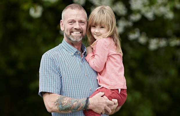 Rob Green smiles while holding his daughter