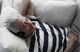 A middle aged man lying on a sofa and listening to classical music