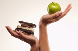 Hands holding an apple and chocolate bars