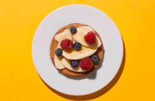 A breakfast of banana, blueberries and raspberries on toast