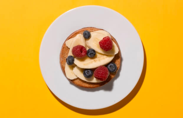 A breakfast of banana, blueberries and raspberries on toast