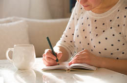 Woman writing down her goals in a notebook
