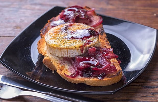 Red onion and goats cheese bruschetta on a plate.
