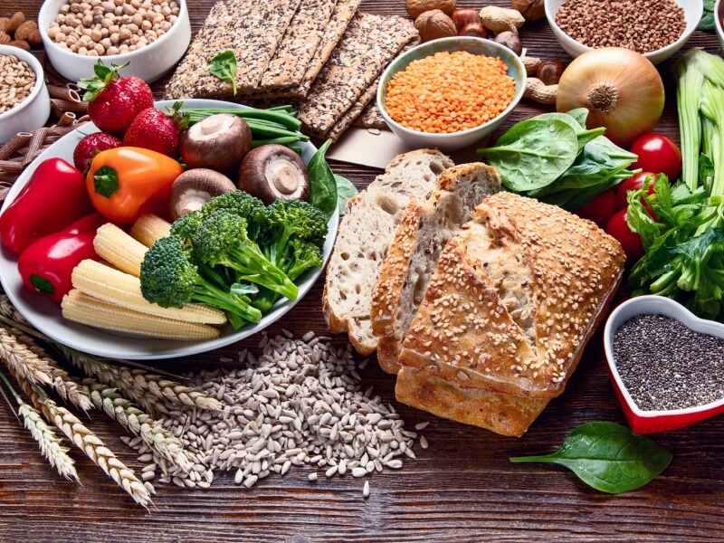 Foods high in fibre, such as vegetables, wholegrains and wholemeal bread, on a table.