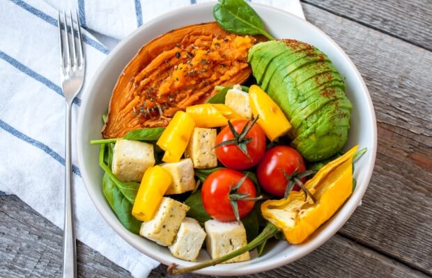 A vegan meal with sweet potato, avocado, spinach, peppers and tofu