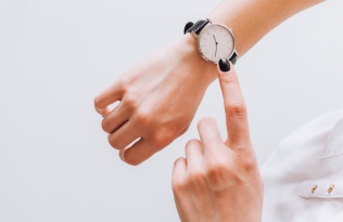 hand pointing at watch on wrist checking time