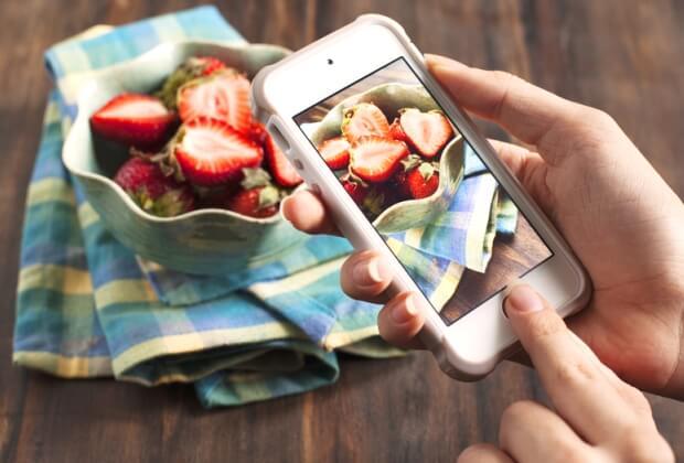 Person photographing strawberries on mobile phone
