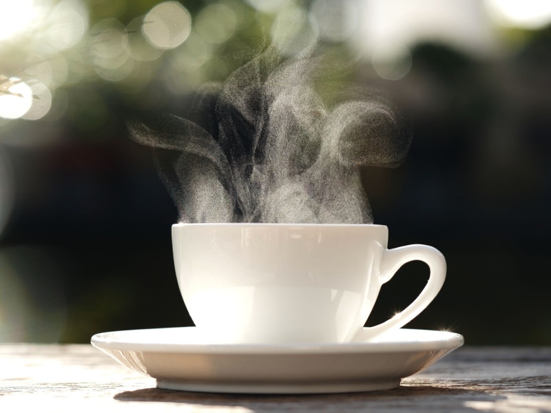 A steaming hot drink in a cup in a saucer.