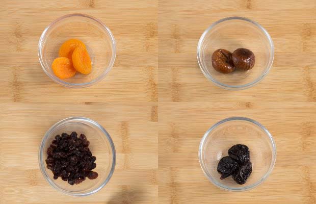 Portions of dried fruits (clockwise from top left - apricots, figs, prunes, raisins)