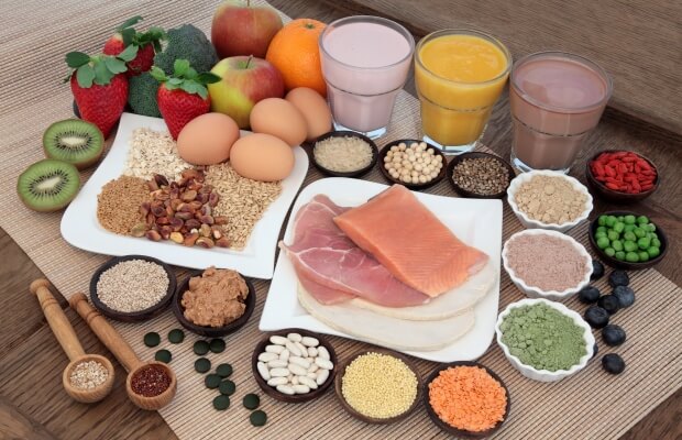 Protein-rich foods laid on a table, including nuts, seeds, legumes, fish and eggs