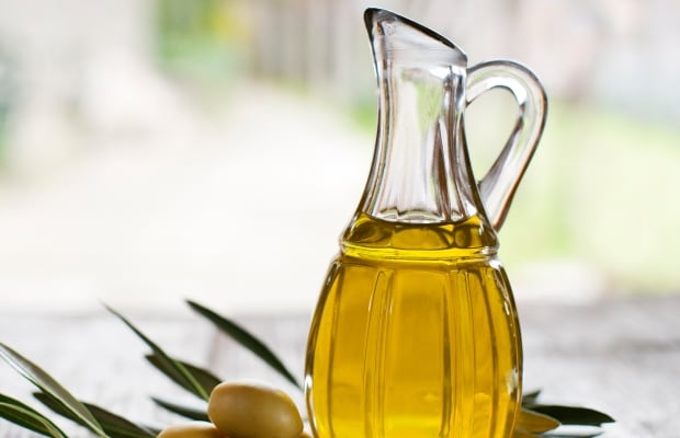 A jug of olive oil and some green olives