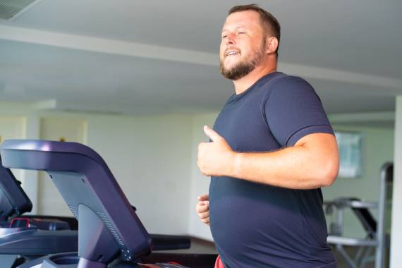 an overweight man using a treadmill 570x380