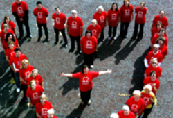 Volunteers wearing red BHF t-shirts, standing in a heart formation with one person in centre