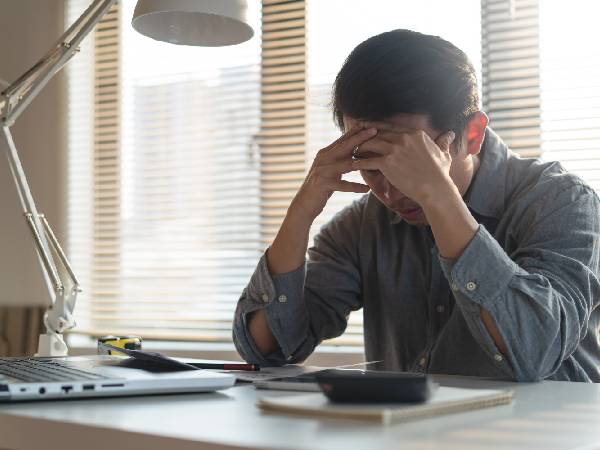 a man sitting at his desk and holding his head in his hands