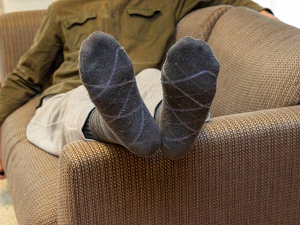 a man lying on a sofa with his legs resting on one of the armrests
