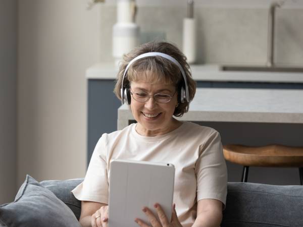 A person happily browsing information on their tablet while wearing headphones