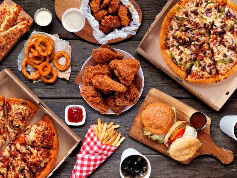 A selection of high cholesterol foods such as pizza and fried chicken.