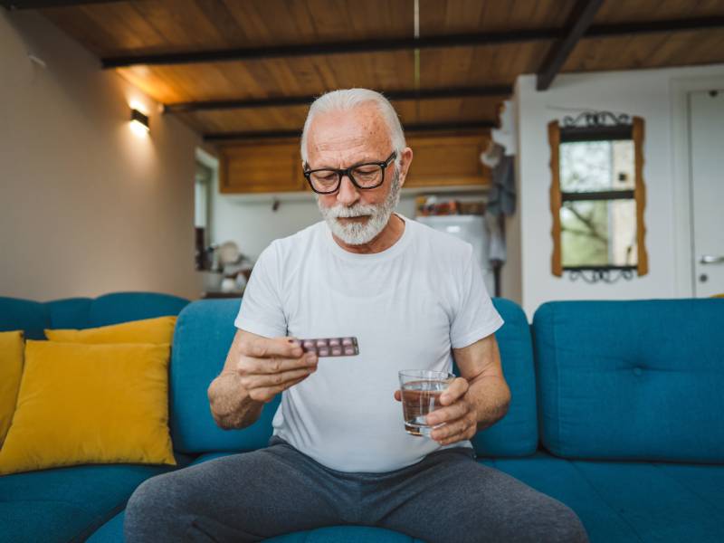 A man inspects a blister pack of medicines.