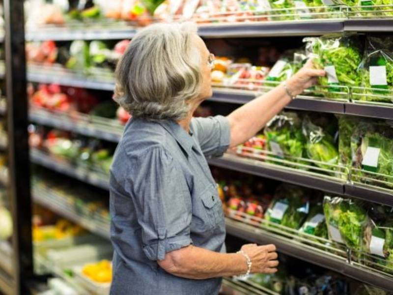 A women picks leafy green vegetables off the shelf at the supermarket.