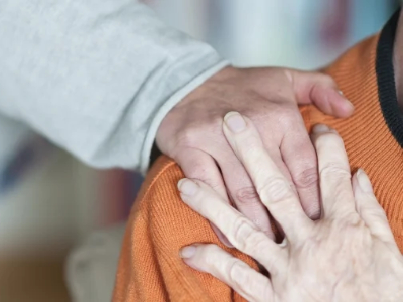 Two hands locked together over someone's shoulder