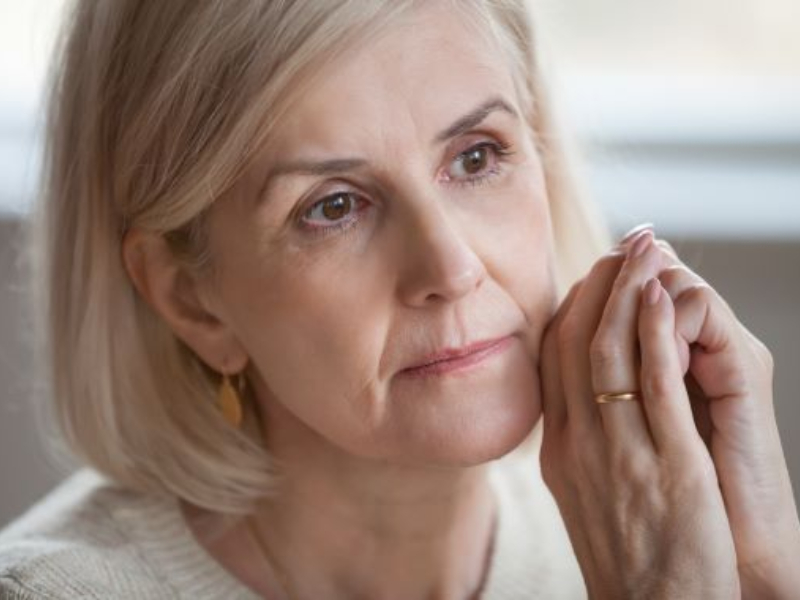 A woman holding her hands together and looking into the distance