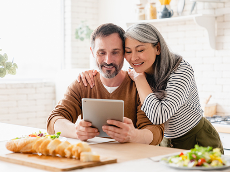 A couple looking at a tablet device and smiling