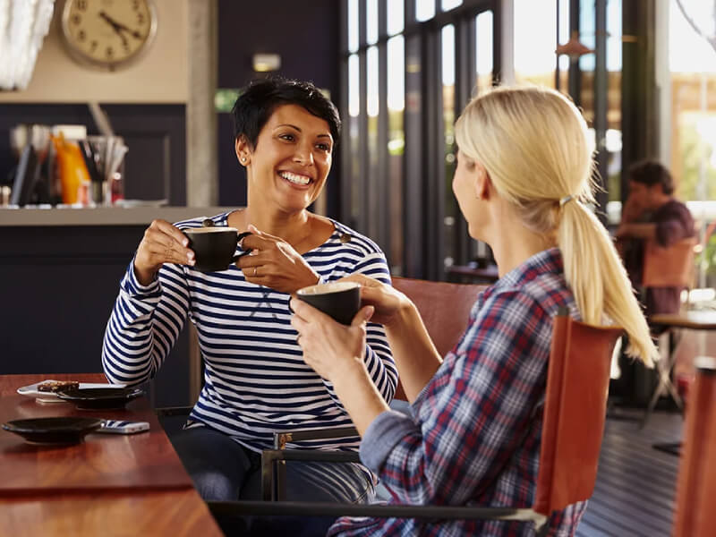Two women sharing a conversation over a hot drink