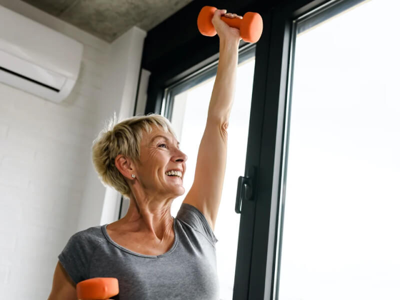 A woman exercises at home using dumbbells