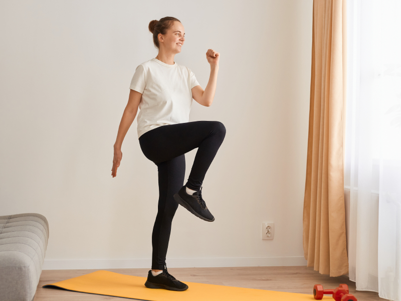 A woman stretching by marching on the spot at home.