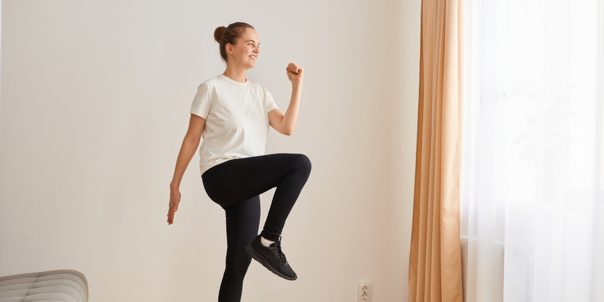 A woman stretching by marching on the spot at home.