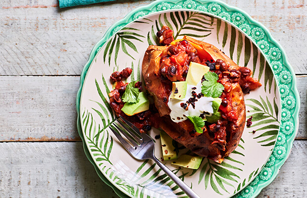 Sweet potato on a plate stuffed with a vegetable chilli containing black beans