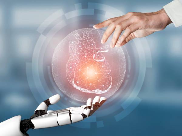 A human hand and robotic hand reaching towards a digital illustration of a heart