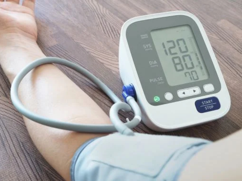 An arm placed on a table with a blood pressure monitor in use