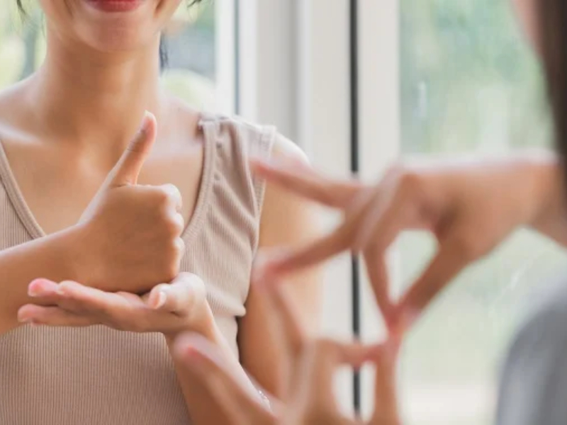 Two people doing sign language together and smiling